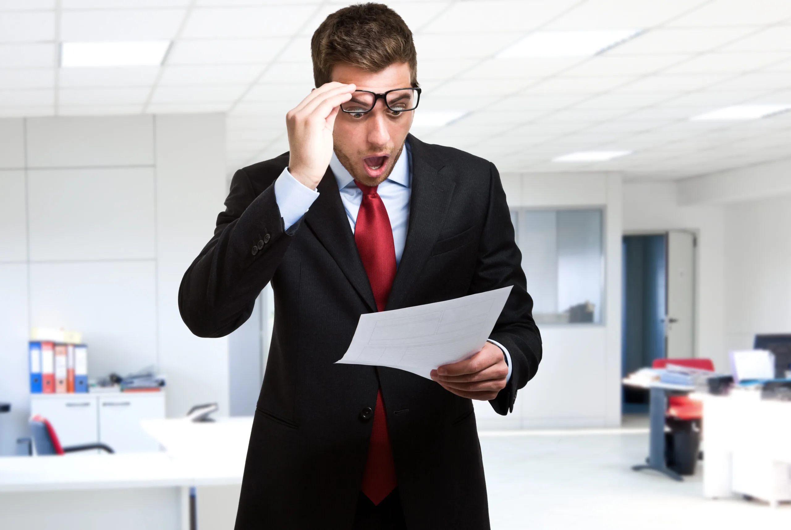 A surprised businessman in a black tuxedo looking at a piece of paper