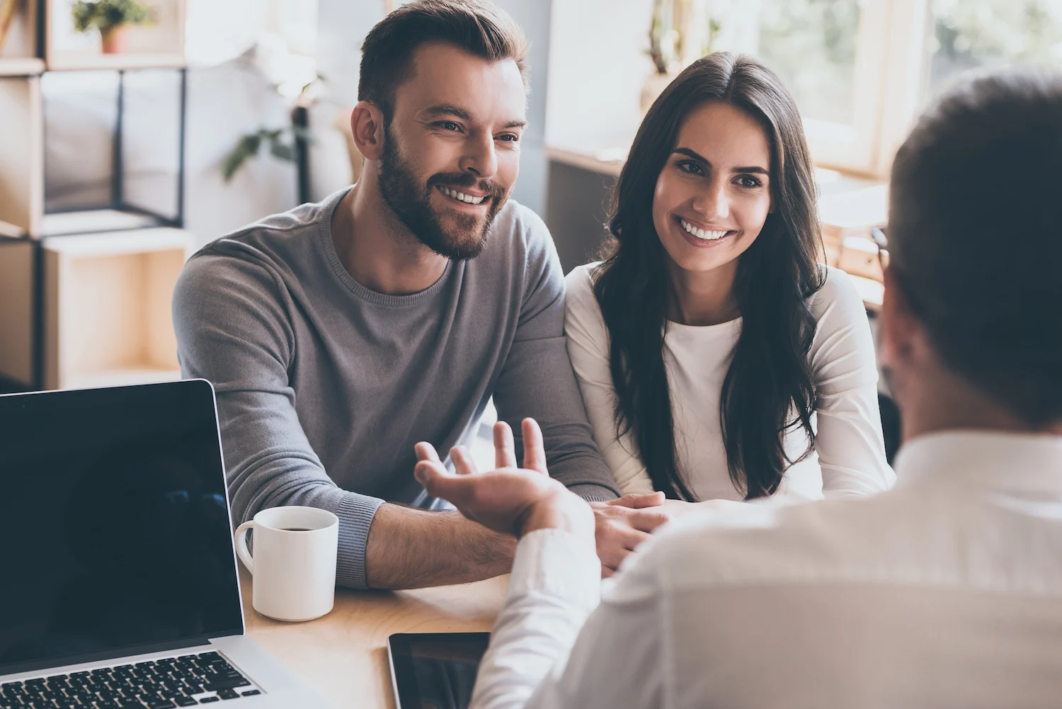 A young couple speaks to a financial advisor inside their office.